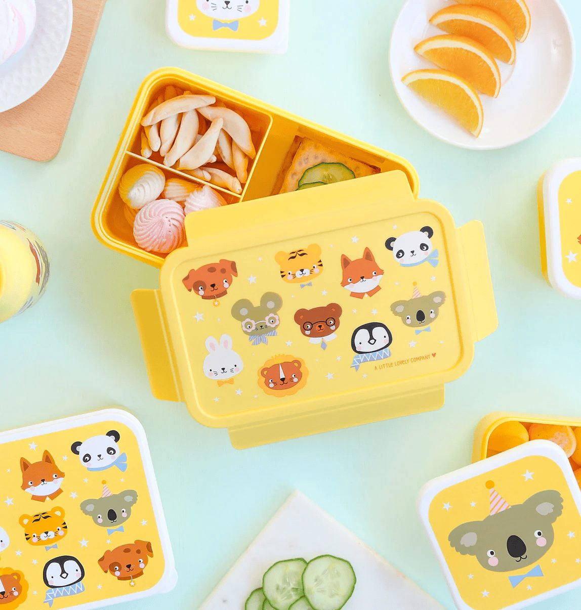 The lunch box is shown open, revealing a removable yellow tray inside divided into two compartments—ideal for a sandwich or main item and snacks. A silicone seal surrounds the lid’s edge, ensuring it closes airtight.