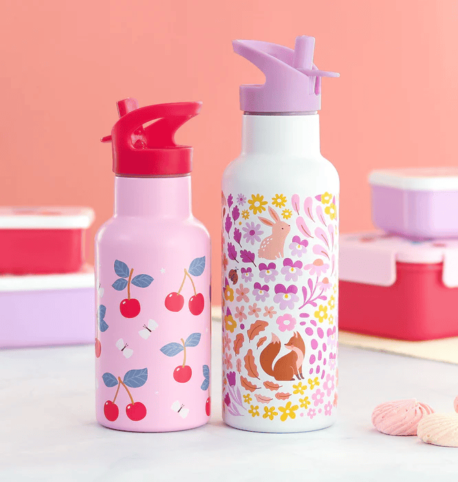 Two bottles (likely one XL size 500 ml and one regular size 350 ml) are placed side by side to highlight size options. The 350 ml size bottle displays the pink cherry motif and red cap, and the 500 ml bottle displays the lilac-colored stainless steel drink bottle decorated with a cheerful floral pattern in pink, yellow, and purple, interspersed with small fox motifs and matching lilac cap, standing against a pale backdrop.